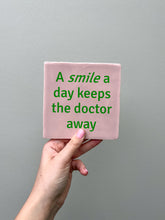 Afbeelding in Gallery-weergave laden, Tegeltje - Roze - A smile a day keeps the doctor away
